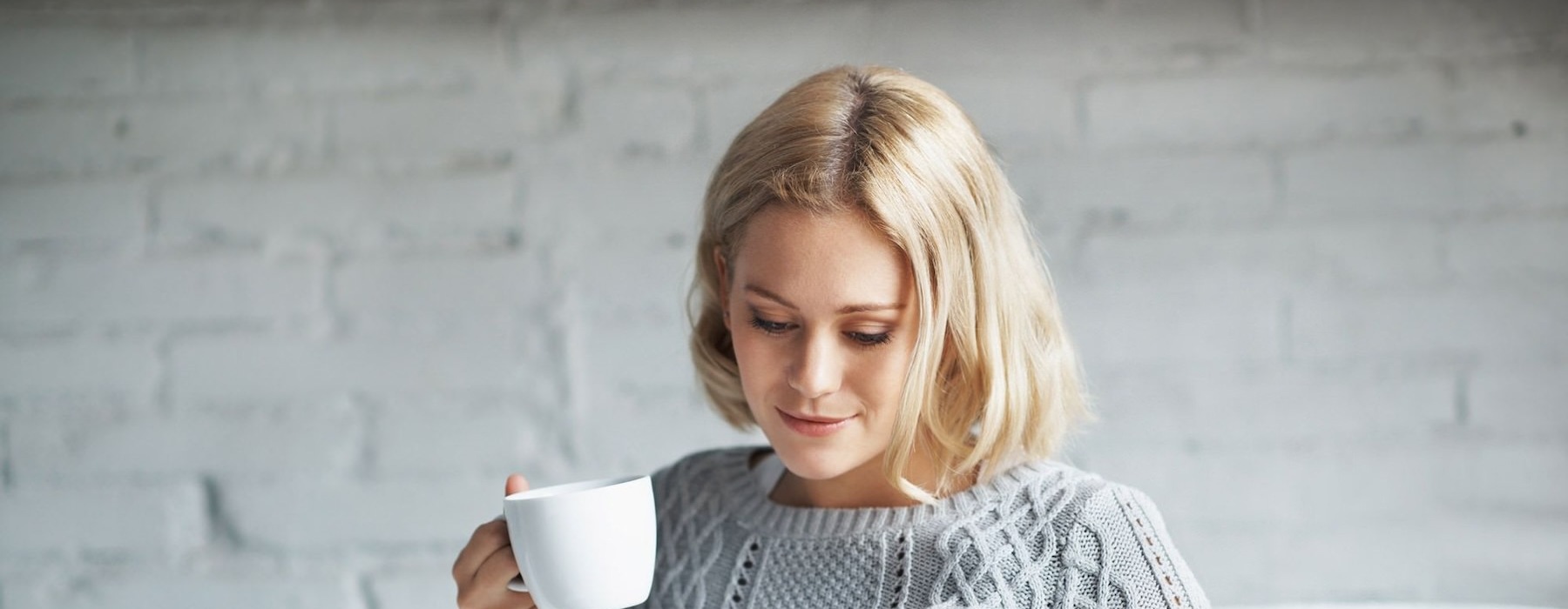 a person sitting down holding a cup looking at a tablet