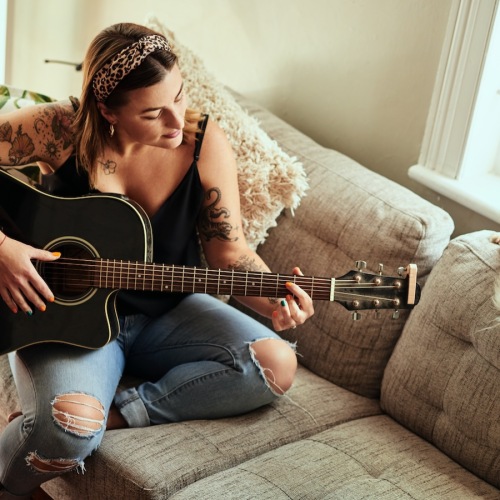 The essence of exceptional living a woman playing the guitar on a sofa