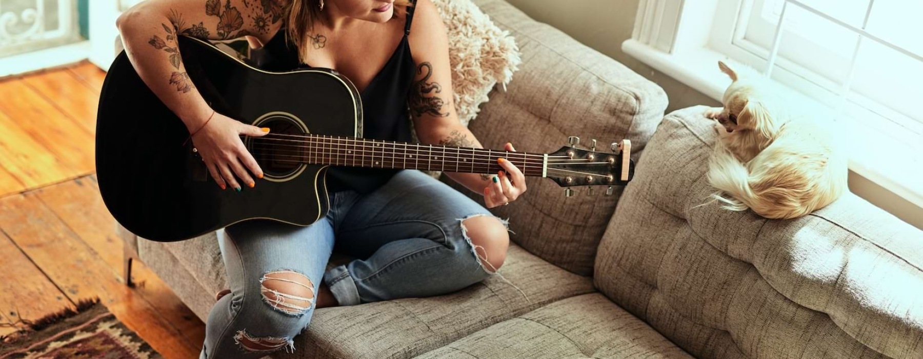 a woman playing the guitar on a sofa