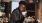 young man smiles while holding a cup of coffee in coffee shop